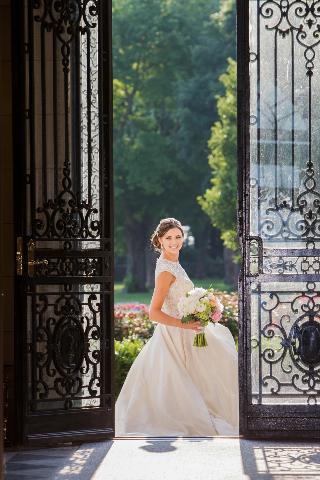 Bride standing in open wrought-iron doors at a mansion entrance