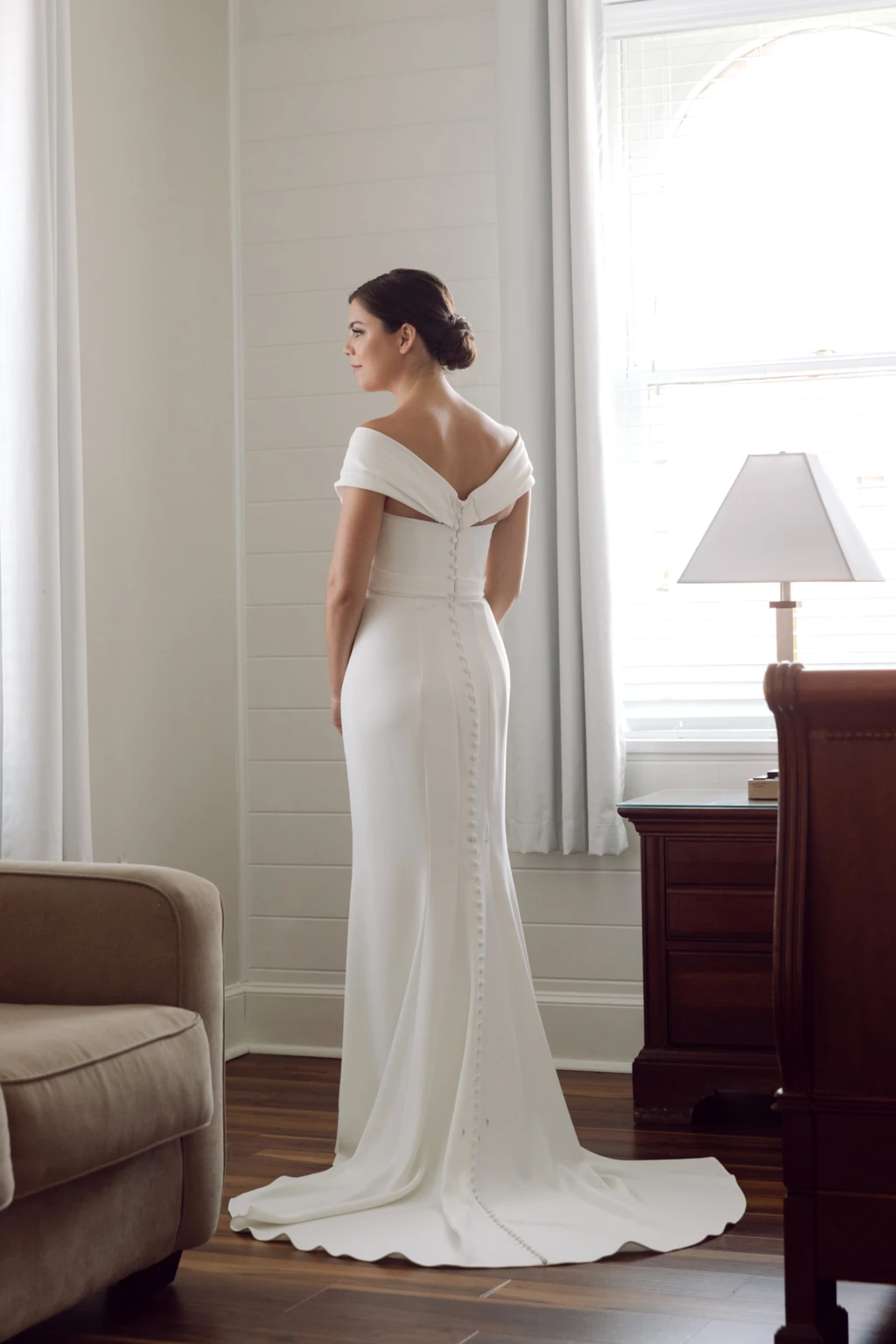 Bride in an off-the-shoulder gown by a sunlit window