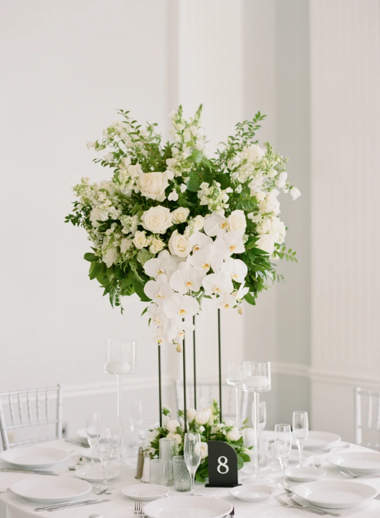 Tall white orchid and rose centerpiece on a reception table