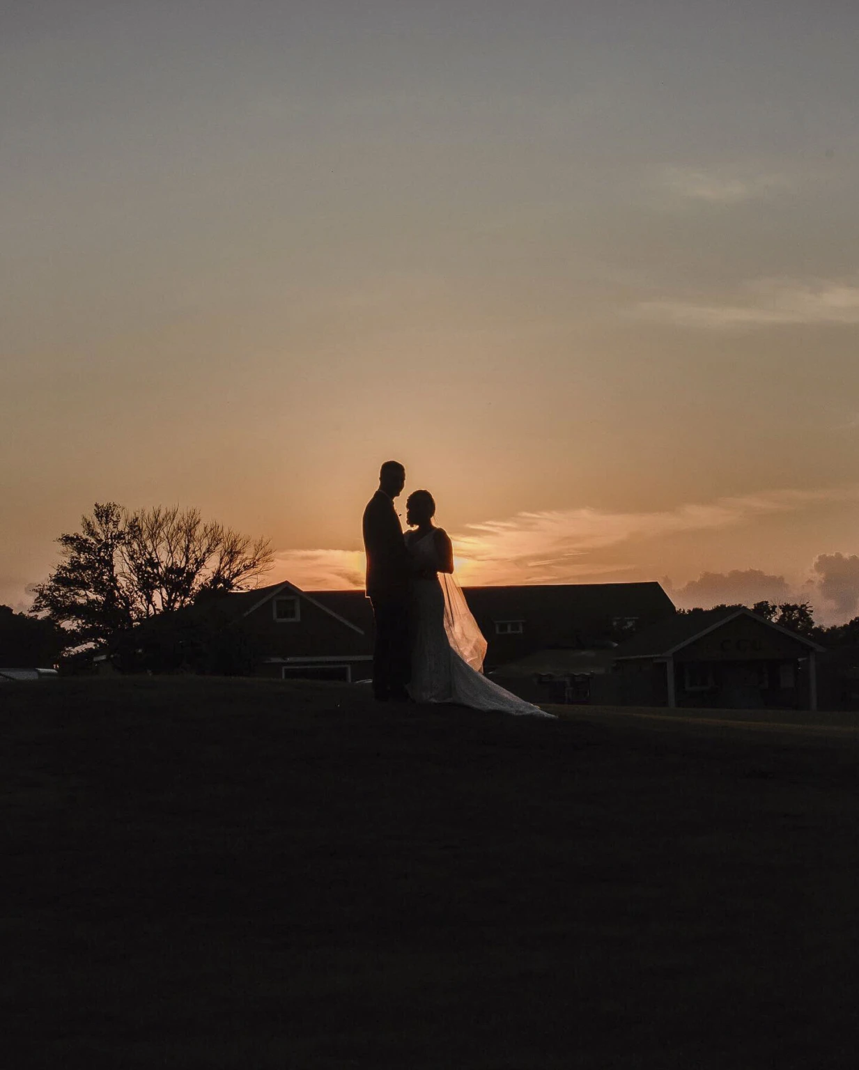Bride and groom silhouetted at sunset