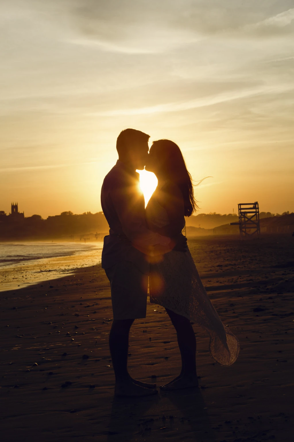 Couple silhouetted kissing on the beach at sunset