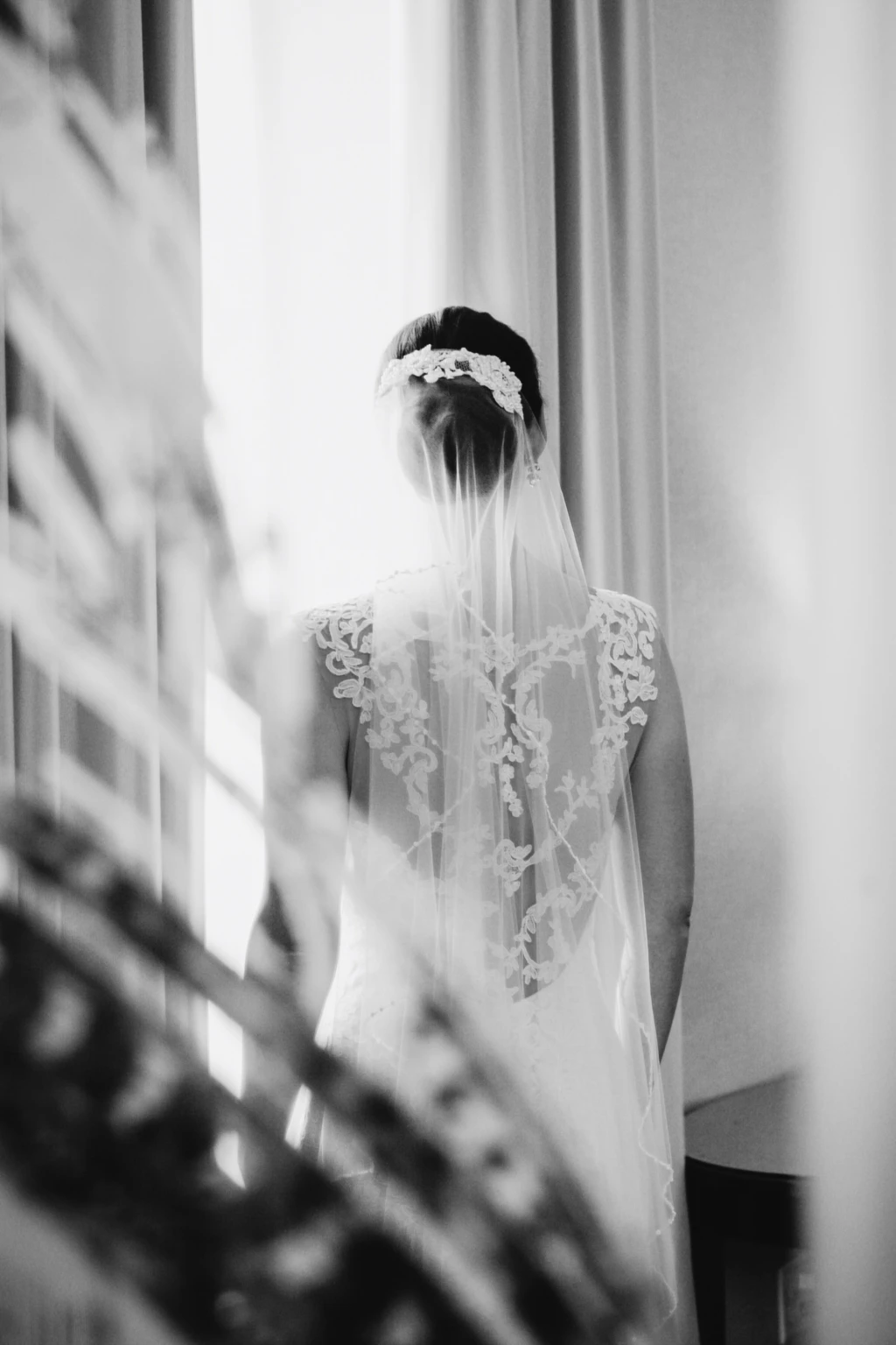 Black-and-white portrait of a bride's lace back and veil