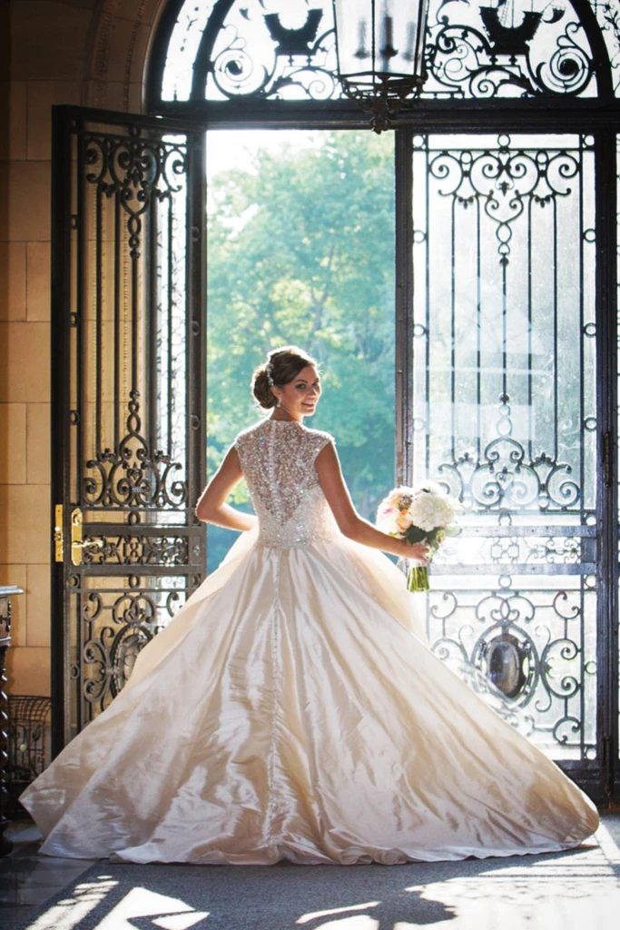 Bride in a ball gown framed by ornate wrought-iron doors